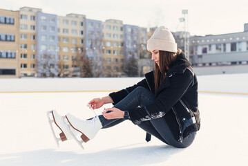 Young pretty and happy woman lying on the ice rink. Winter holidays.