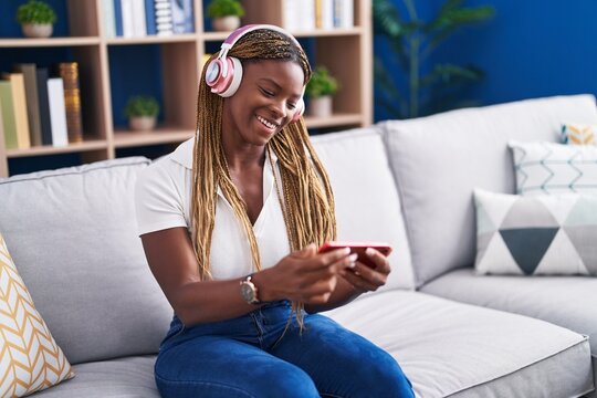 African american woman playing video game sitting on sofa at home
