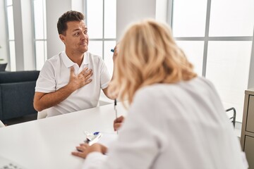 Middle age man and woman doctor and patient using inhaler having medical consultation at clinic