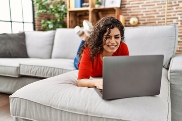 Naklejka premium Young latin woman smiling confident using laptop at home