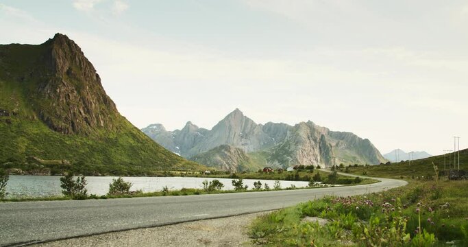Lake and mountains landscape scenic view on a sunny day. Road and grass with in the foreground. Lofoten, the beautiful nature of the fjords of Norway. Low angle view.
