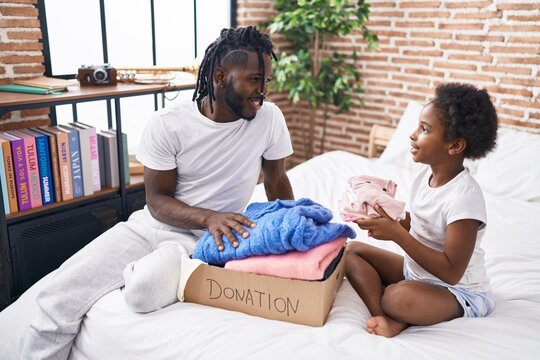 Father and daughter folding clothes to donate at bedroom