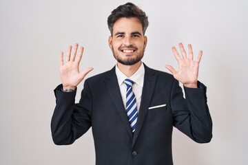 Young hispanic man with tattoos wearing business suit and tie showing and pointing up with fingers number ten while smiling confident and happy.