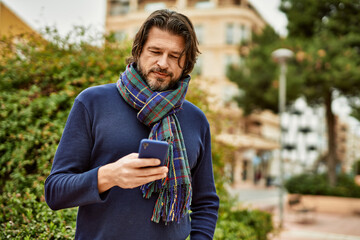 Fototapeta premium Middle age handsome man using smartphone outdoors at the park