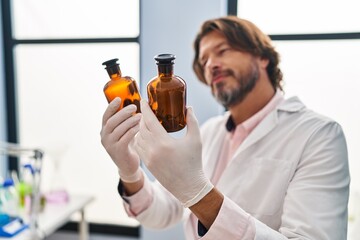 Middle age man scientist holding bottles at laboratory