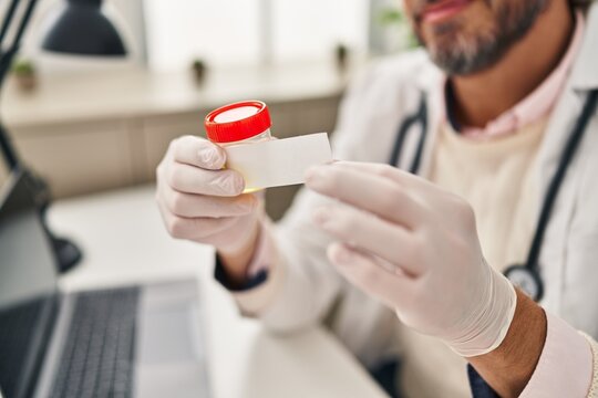 Middle age man doctor putting sticker on urine test tube at clinic