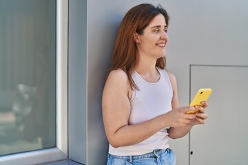 Young woman smiling confident using smartphone at street