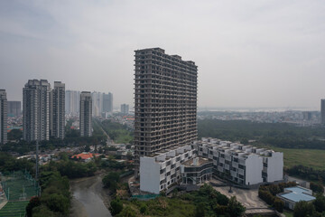 Fototapeta premium Aerial angled view of large abandoned concrete shell of residential high-rise real estate and construction development with view to river