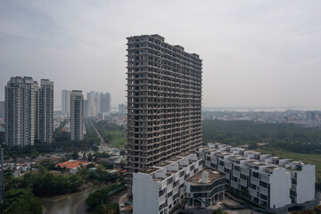 Aerial angled view of large abandoned concrete shell of residential high-rise real estate and...