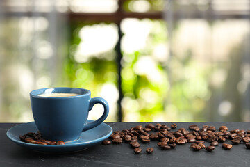 Cup of aromatic coffee and beans on grey table indoors