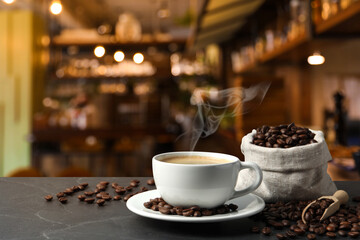 Cup of aromatic coffee and beans on grey table in cafe