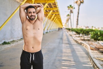 Hispanic man stretching after working out outdoors on a sunny day