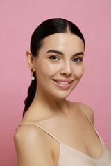 Young woman wearing elegant pearl earrings on pink background