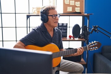Middle age man musician singing song playing classical guitar at music studio