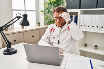 Senior doctor man working on online appointment pointing unhappy to pimple on forehead, ugly...