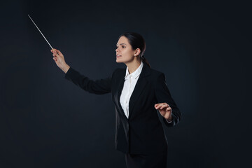 Professional conductor with baton on dark background