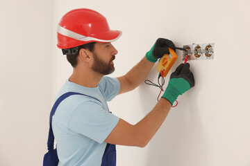 Professional electrician with tester checking voltage indoors