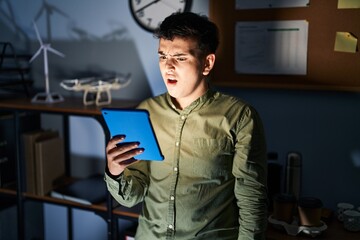 Non binary person using touchpad device at night in shock face, looking skeptical and sarcastic,...