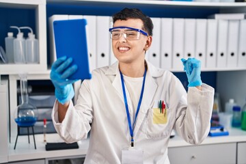 Non binary person working at scientist laboratory using tablet screaming proud, celebrating victory...