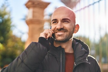 Young man smiling confident talking on the smartphone at street