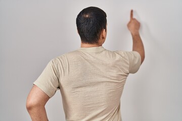 Young arab man wearing casual t shirt posing backwards pointing ahead with finger hand