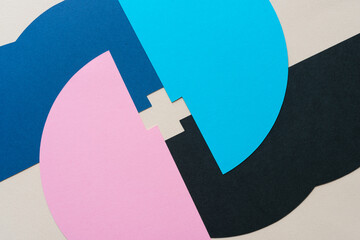 pink, blue, and black paper shapes overlapping and forming the letter X or a cross at center