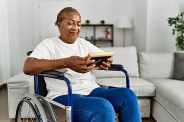 Senior african american woman looking photo sitting on wheelchair at home