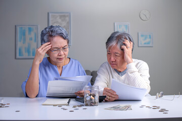 Worried Asian senior family couple reading financial documents or notification letter with bad news...