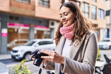 Young beautiful hispanic woman wearing scarf using professional camera at street