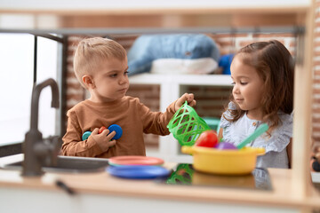 Adorable girl and boy playing with food plastic toy sitting on table at kindergarten