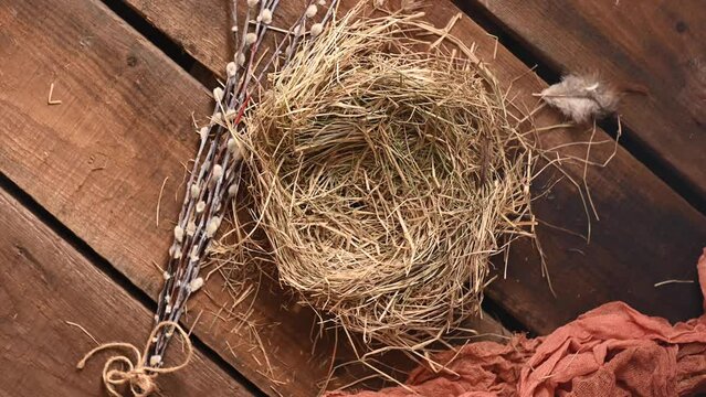 An empty bird nest and willow branches on a wooden surface. Easter design, place for inscription. High quality 4k footage