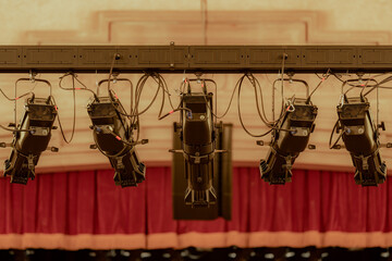 Closeup photo of five new large theater spot lights hung within an older theatre or auditorium.