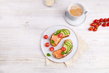 Homemade breakfast with fish and cup of coffee. Healthy toasts with rye bread with salted salmon, avocado, cream cheese, fresh tomatoes, sesame seeds. Top view. 