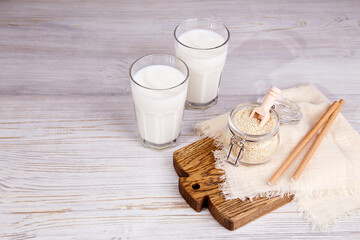 Sesame milk in glasses, sesame seeds in a jar on a wooden background. A healthy vegetarian and vegan drink, a plant-based milk substitute. 