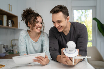young couple man and woman starting home security surveillance camera - obrazy, fototapety, plakaty
