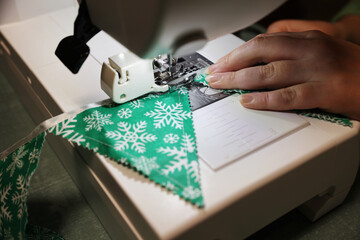 Woman sews green festive flag, home hobby crafting christmas decorations