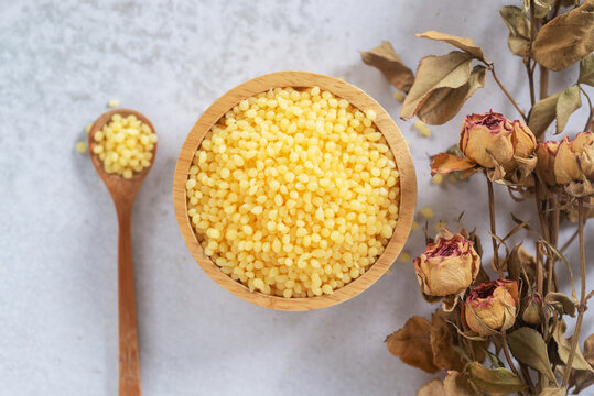 Candelilla wax  in wooden bowl on white marble background