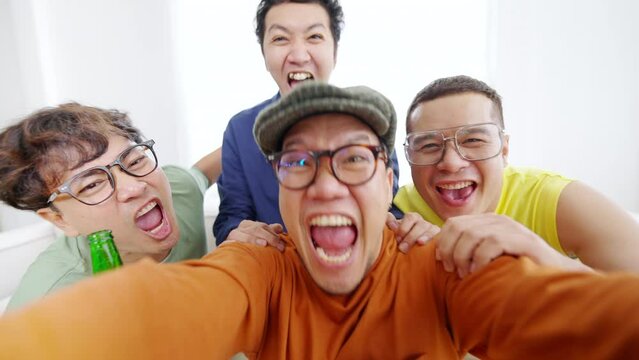 4K Group of Asian man friends watching world soccer games football competition on television with drinking beer together at home. Sport fans shouting and celebrating football team victory the match