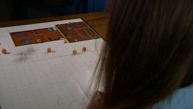 Woman Rolls Handful of Dice on a Game Mat With RPG Accessories
