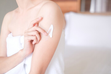 Obraz na płótnie Canvas Asia woman sitting on bed and applying cream on arm