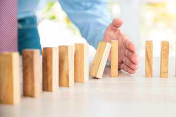 Close-up hand prevent wooden block not falling domino concepts of financial risk management and strategic planning and business challenge plan.