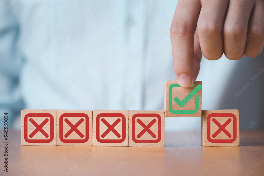 Poster businessman holding green correct sign mark among red cross mark which print screen on wooden cube b