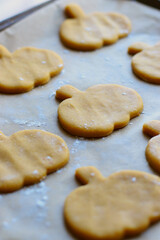 Fototapeta na wymiar cut out cookies shapes of raw pumpkin dough on baking sheet