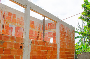 Brick wall under construction of brazilian house, brick under construction in brazil. blocks or bricks (masonry) of red clay on a wall, in the work of Brazilians.