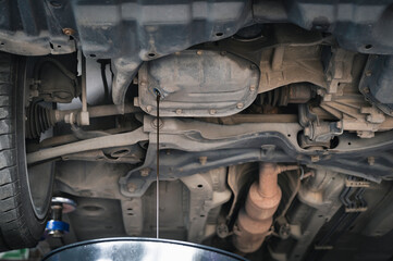Auto mechanic draining automotive engine oils ,engine oil change in garage services.