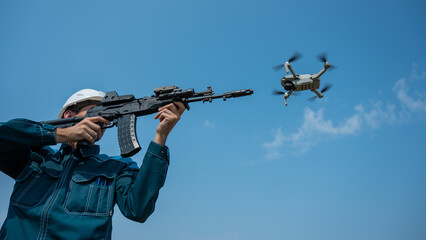 Caucasian man in a helmet shoots a flying drone with a rifle. 