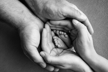 Children's foot in the hands of mother, father, parents. Feet of a tiny newborn close up. Little...