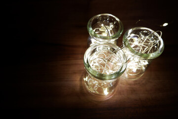 Glittering illumination lighting in a glass bottles on darkness. Simple lighting photo for holiday decorations.