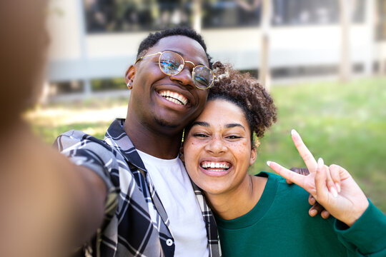 Happy African American young couple taking selfie outdoors in a park.