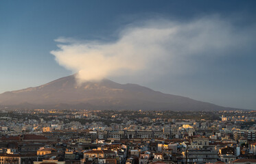 Port of Catania. Volcano Etna with white smoke and blue sky on background. Sicily, Italy